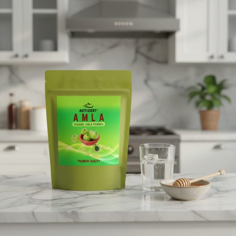 ACTIZEET Amla powder on a marble counter with a bowl of honey and glass of water.