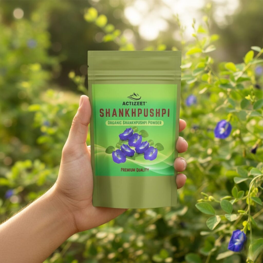 A hand holding an ACTIZEET Shankhpushpi pouch in a lush green garden setting