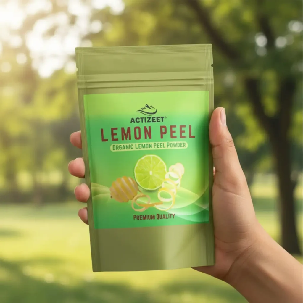 A well-groomed Indian hand holding the ACTIZEET lemon peel powder pouch against a blurred green background